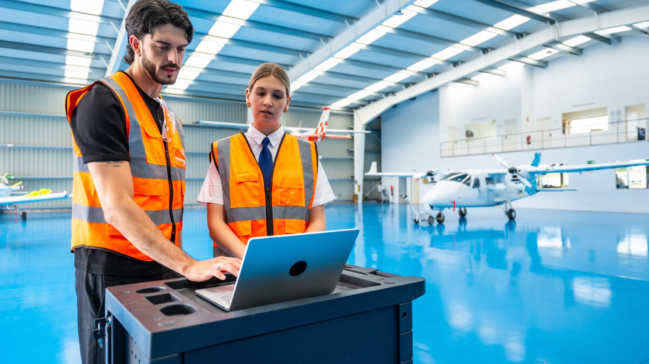 Two aerospace professionals with an aircraft in background, representing a company that overcame a tech talent shortage.