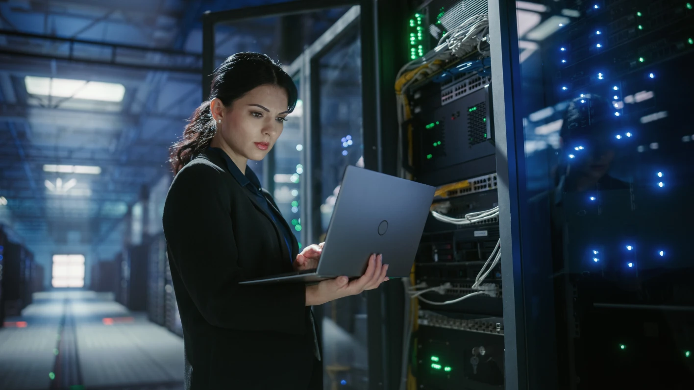 A female IT engineer with in-demand skills uses a laptop to monitor servers. 