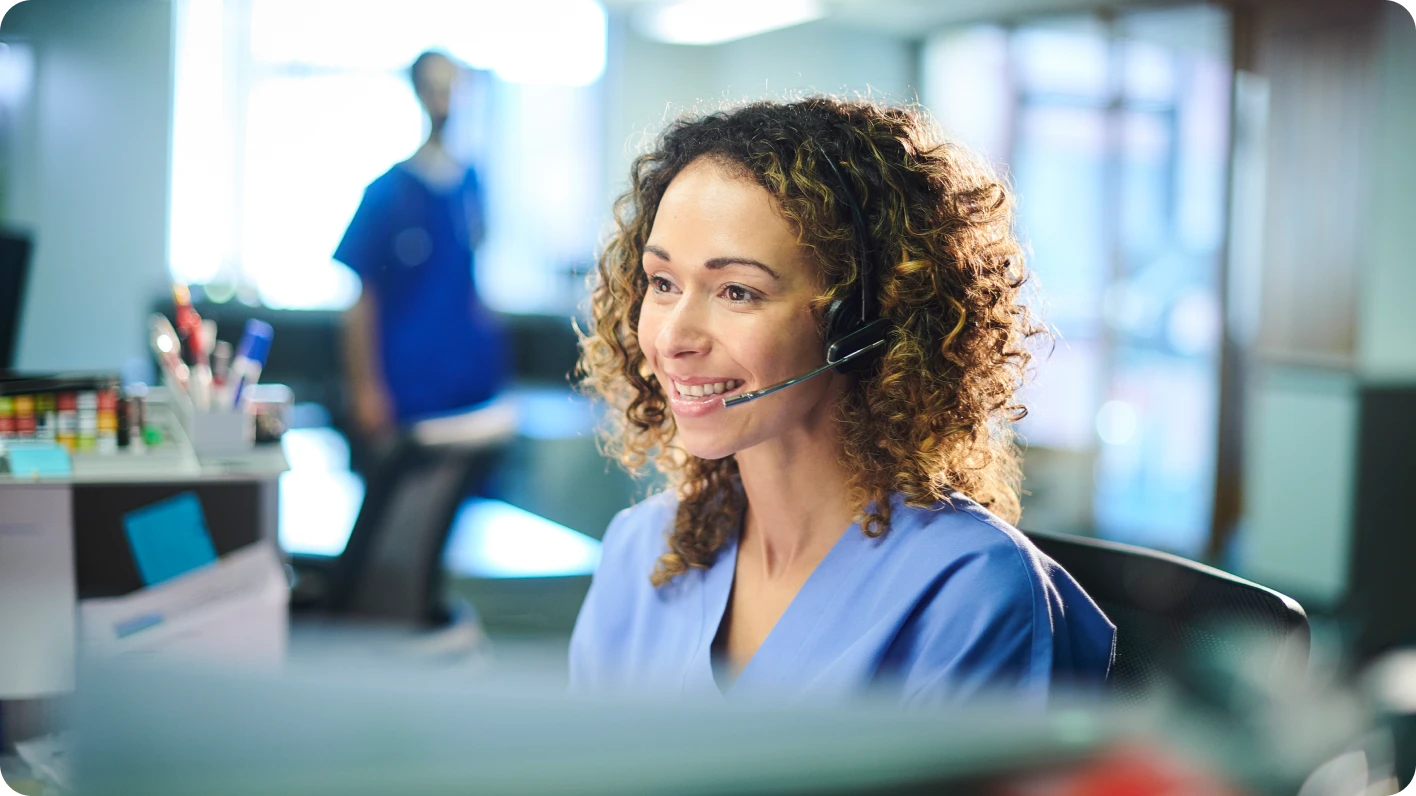 woman smiling with headset at computer desk