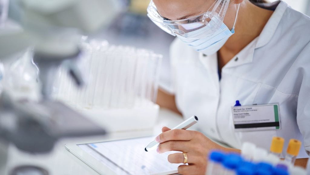 female scientist in a lab taking notes on a tablet