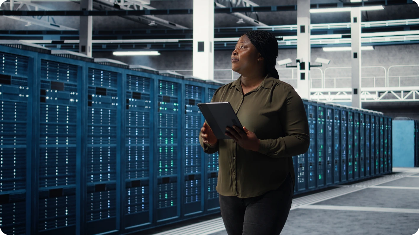 A woman with a tablet working in a data center, representing how people fuel the North American data center boom.