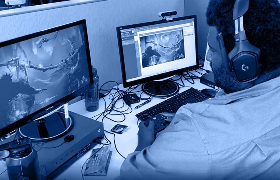 A video game tester sits at desk and tests games for bugs