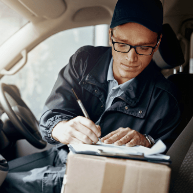 Male mechanic inside car writing on a clipboard