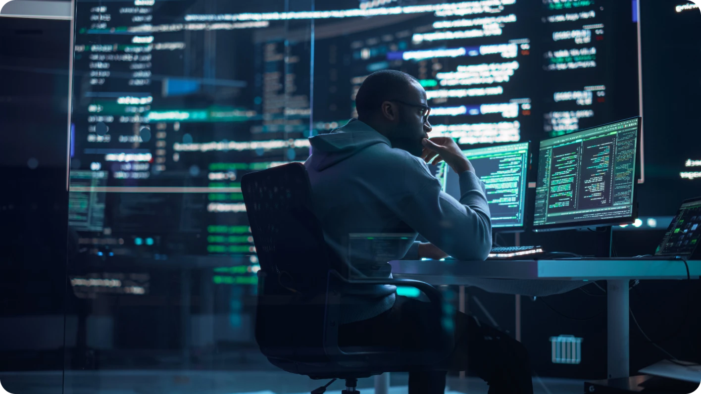 coder sitting at console with multiple screens
